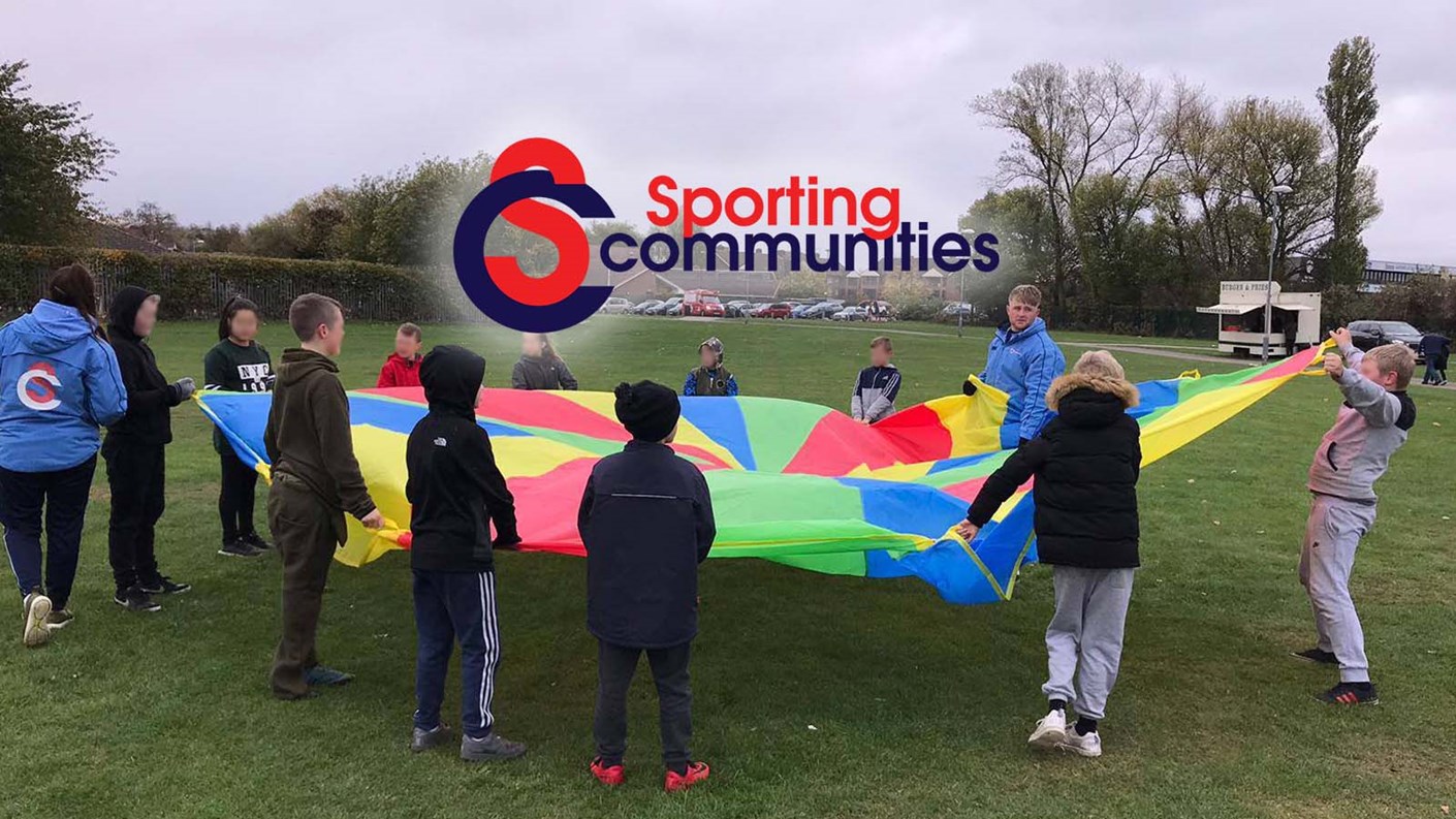 Sporting Communities - A group of children playing with a large parachute