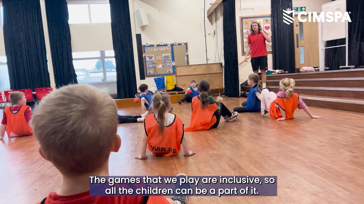 A group of children sit listening to a coach