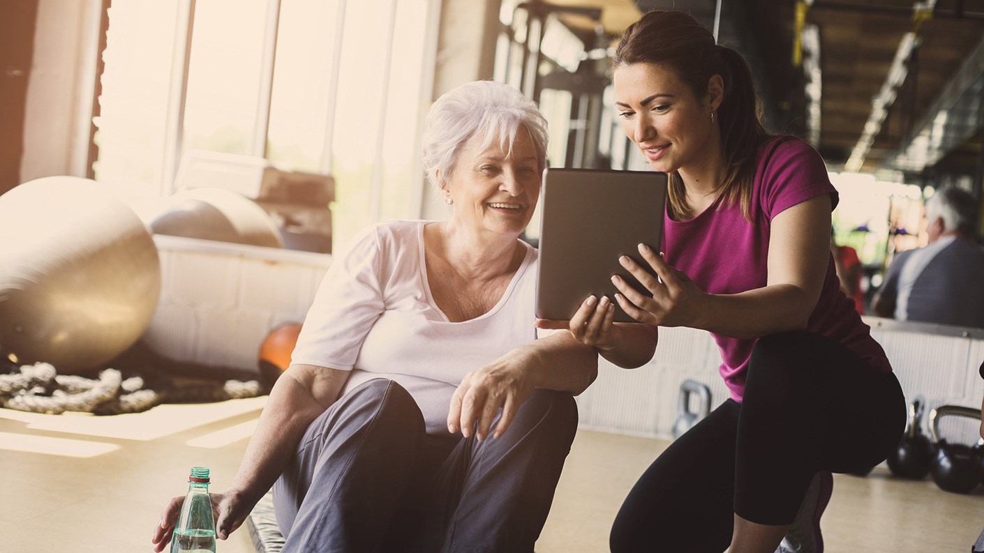 Exercise Instructor using a tablet to advise older lady