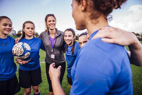 A group of teenage girls and their coach on the football field