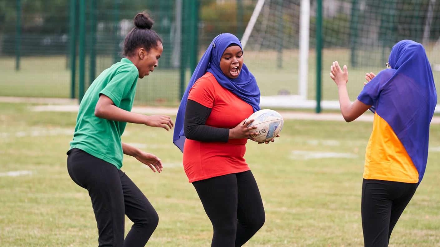 Three young women playing rugby