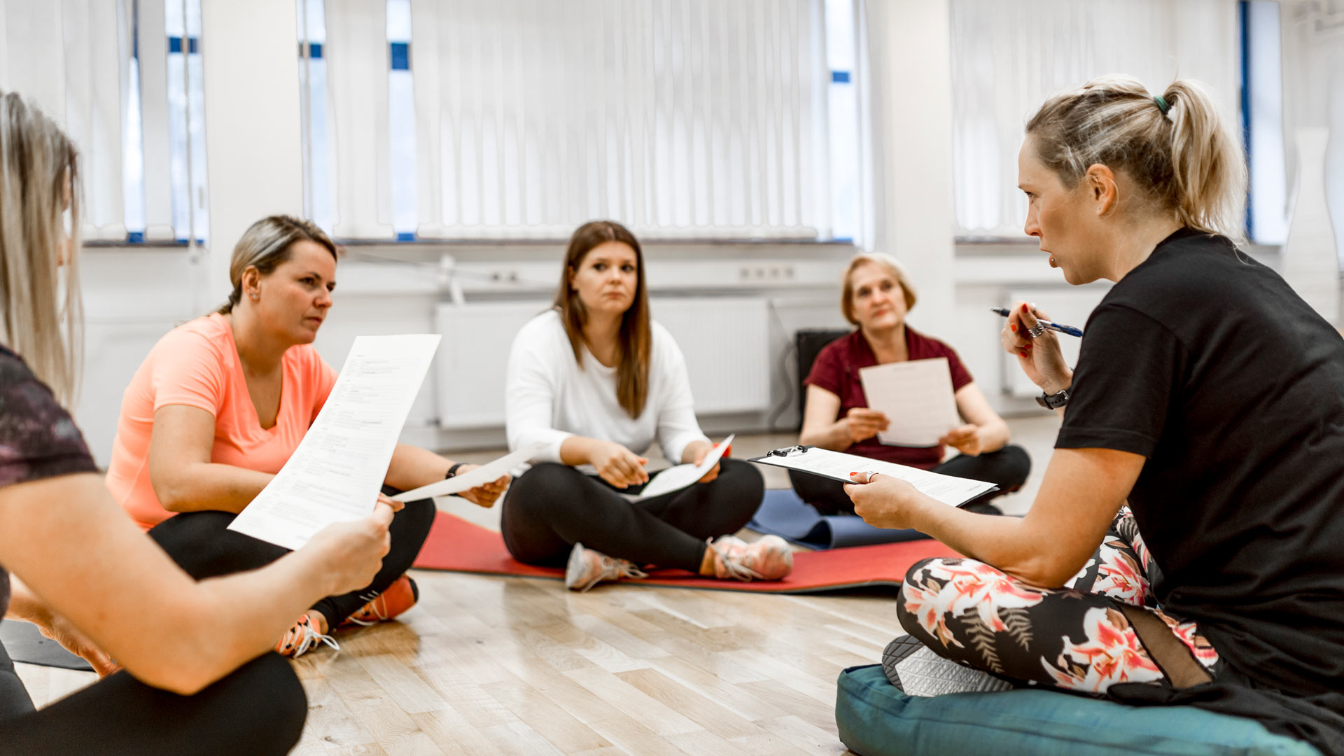 women sat on gym floor with paperwork