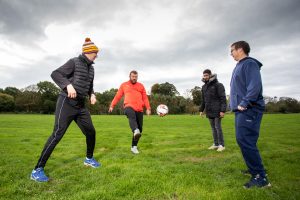 Four men having a kickabout on football field